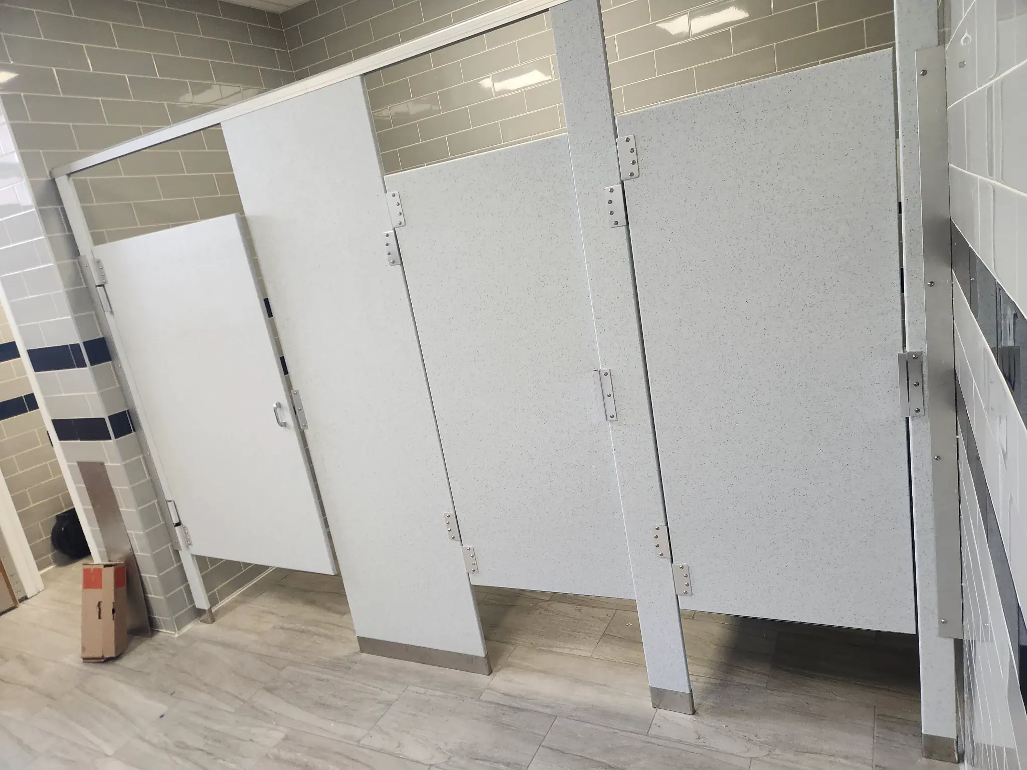 Three white solid-plastic commercial restroom stalls at Hewlett-Woodmere Public Schools in Woodmere, New York