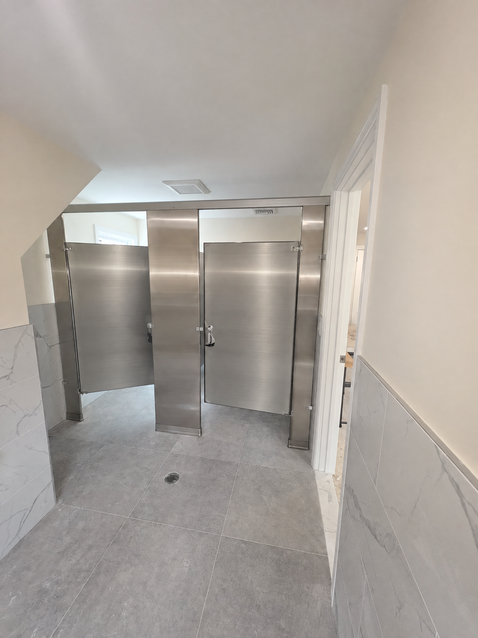 Four stainless-steel commercial restroom stalls at Robert Spearing Funeral Home in Park Ridge, New Jersey