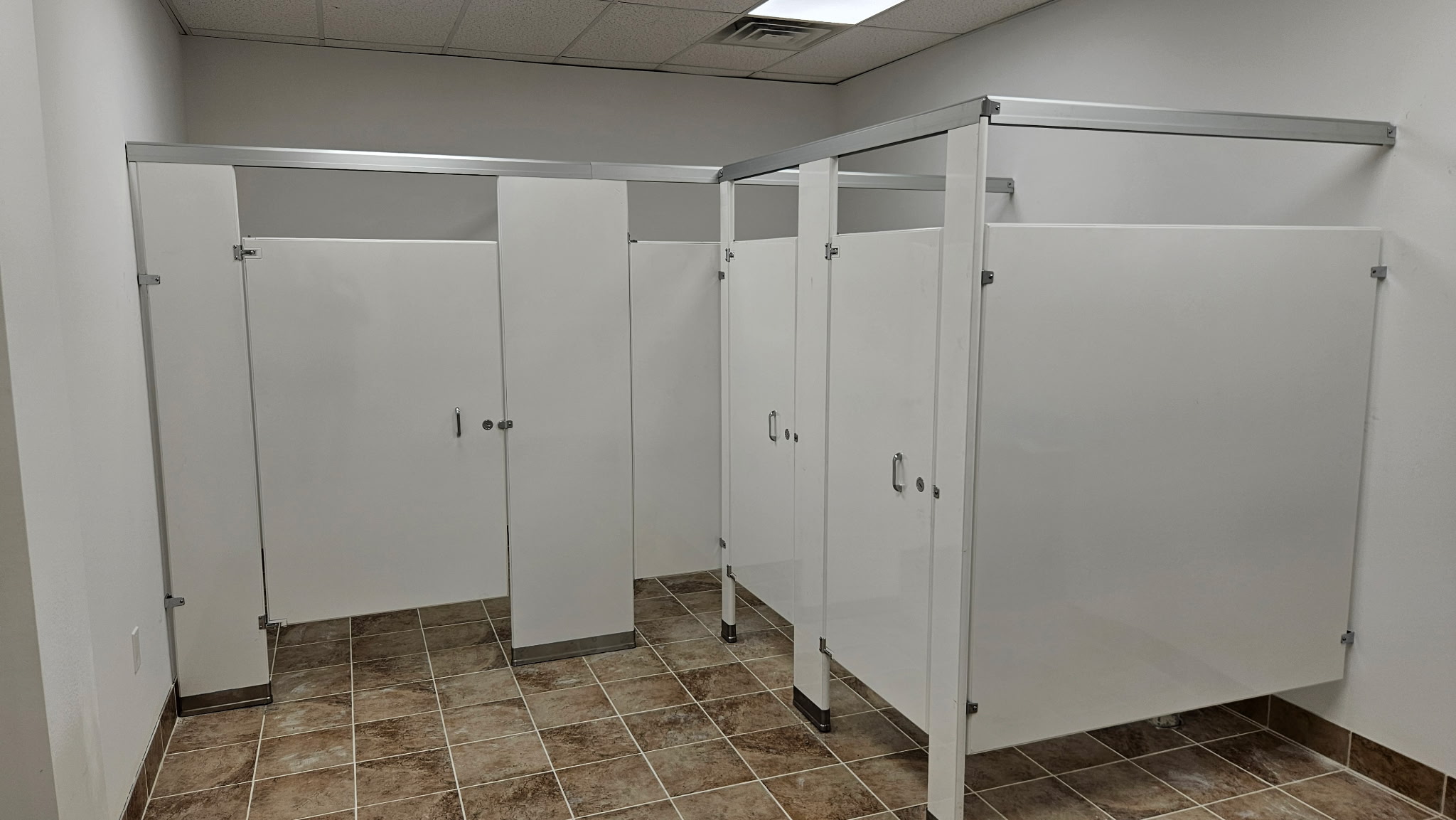 Wider view of white solid-plastic HDPE commercial restroom stalls at the YouthBuild Newark project in Newark, New Jersey